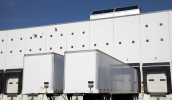 Two trailers parked outside of a warehouse