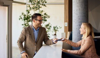 A receptionist handing over a card to a man