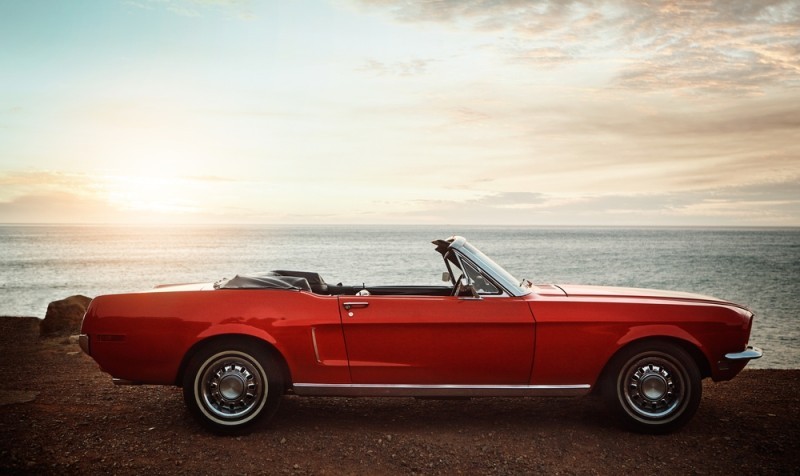 red classic car with sunset behind it
